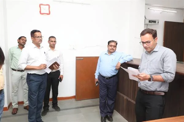 तहसील कार्यालय के भीतर हाथ में कागज लेकर पढ़ते अधिकारी और पास खड़े अन्य अधिकारी