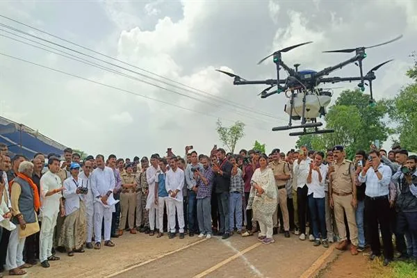 सड़क पर लोगों और पुलिसकर्मियों की मौजूदगी के बीच हवा में उड़ता कृषि ड्रोन