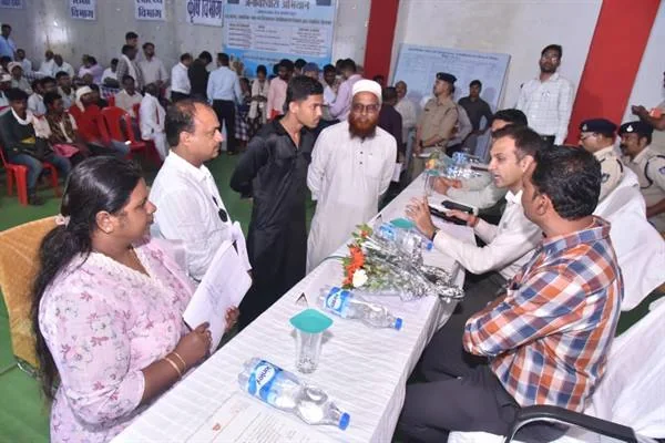 सभागार में मेज के दोनों ओर बैठे और खड़े लोग आवेदन पर चर्चा करते हुए, पीछे पुलिसकर्मी और अन्य उपस्थित लोग