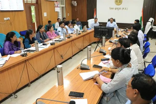 झाबुआ कलेक्टर कार्यालय के सभाकक्ष में मेज के दोनों ओर बैठे अधिकारी समीक्षा बैठक में भाग लेते हुए