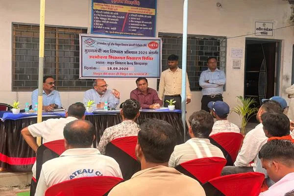 भवन के बाहर लगे शिविर में मेज पर बैठे अधिकारी और सामने कुर्सियों पर बैठे लोग