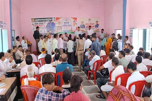 सभागार में मंच के सामने अधिकारियों और ग्रामीणों की भीड़, लाल कुर्सियों पर बैठे लोग और पीछे अभियान के बैनर